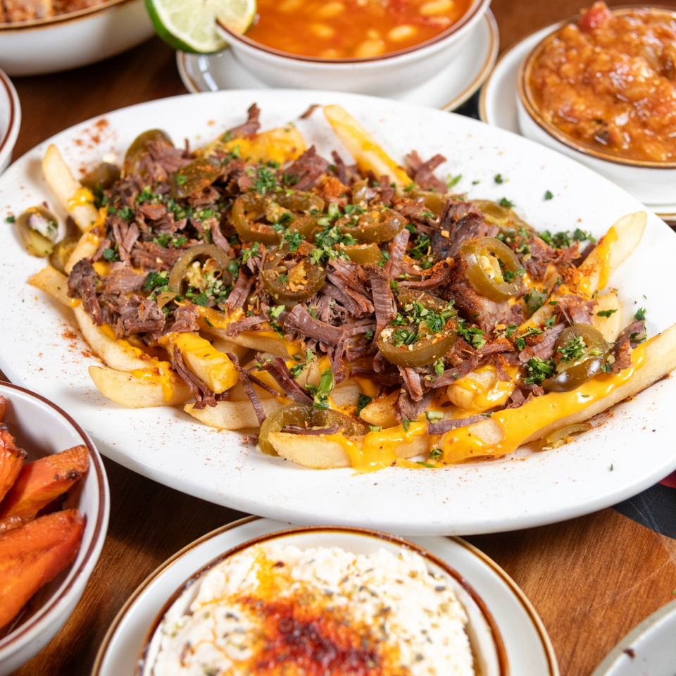 Loaded fries with shredded beef, melted cheese, sliced jalapeños, and chopped parsley.